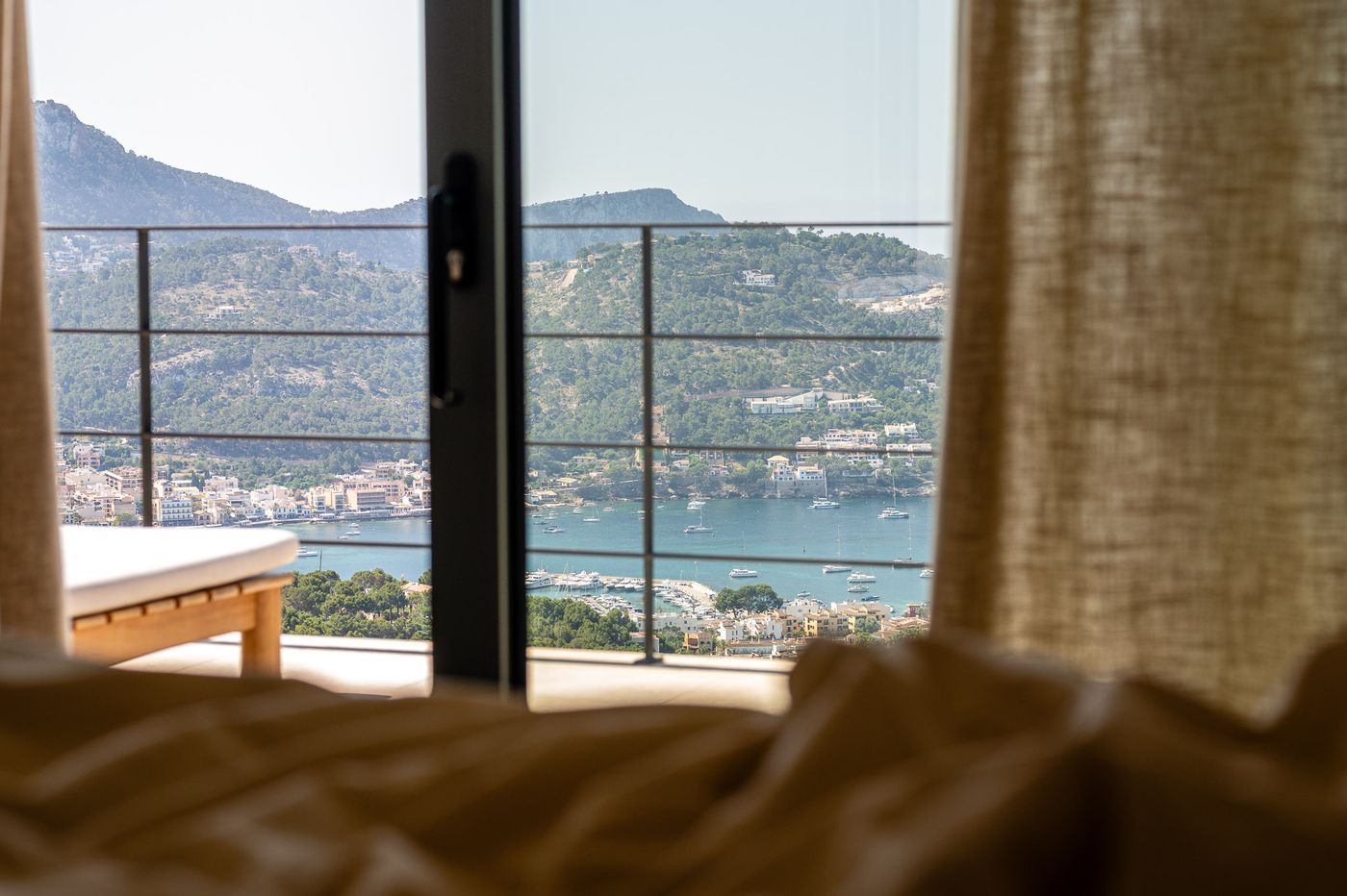 First-floor suite opening to the bay view through soft curtains
