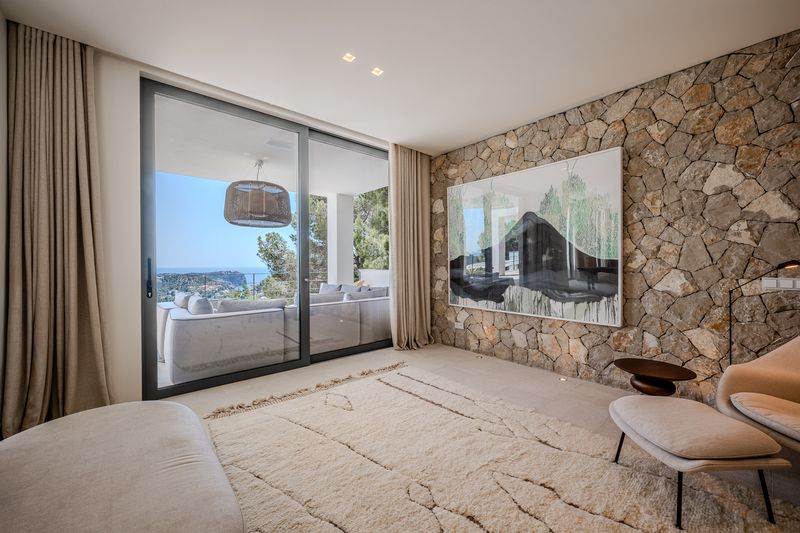 Living room with a natural stone wall and panoramic glazing